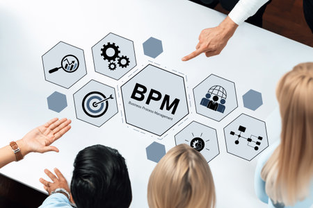 A diverse team collaborates on a business process management strategy using graphics and icons on a sleek table in a contemporary office.の写真素材