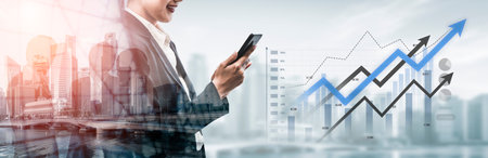 A business professional studies financial data on a smartphone with upward trends displayed,...