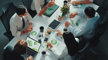 Top view of manager hold tablet display clean energy investment at meeting. Aerial view of skilled business team working together and planning to use sustainability environmental energy.の写真素材