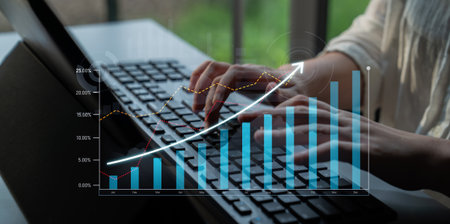 A close-up view of hands typing on a keyboard, with an overlay of growing data analysis graph,...
