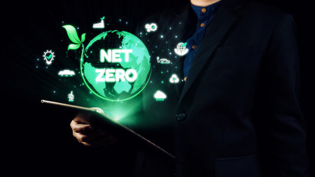 A business professional holds a tablet showcasing a green globe with a net zero graphic, emphasizing...