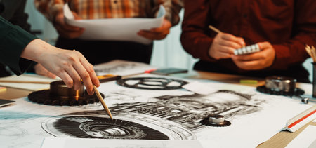 A diverse team collaborates on an engineering design, sketching detailed plans and illustrations on...