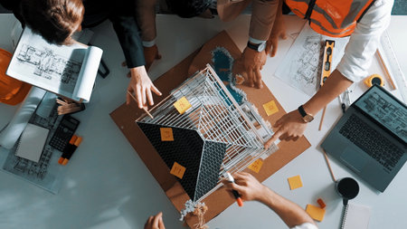 Top down aerial view of smart architect engineer team inspect house model while manager hold...