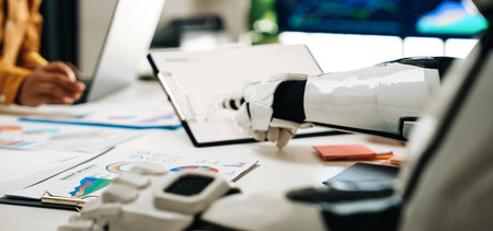 A modern workspace featuring a close-up of a robot hand collaborating with a human during a meeting,...