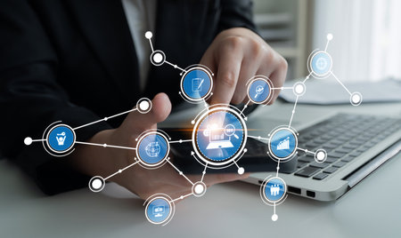 A business person interacts with a laptop, illustrating a digital network of icons that represent various aspects of online commerce and connectivity in a modern workspace.の写真素材