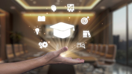 A hand holds a graduation cap icon amidst glowing educational symbols, reflecting the merging of learning and innovation in a modern office environment.の写真素材