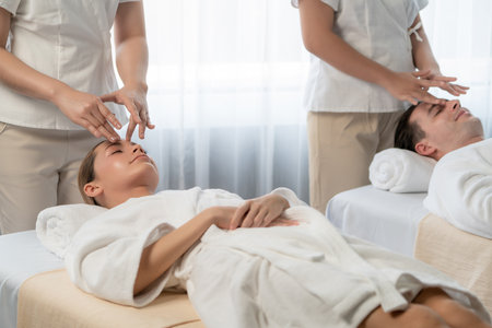 Caucasian couple enjoying relaxing anti-stress head massage and pampering facial beauty skin recreation leisure in dayspa modern light ambient at luxury resort or hotel spa salon. Quiescentの写真素材