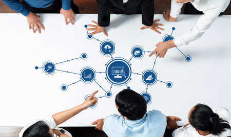 A diverse team collaborates over a table filled with infographics, charts, and data analysis...