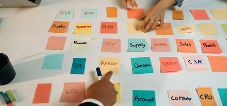 A dynamic office scene showcasing a brainstorming session with colorful sticky notes on a table,...