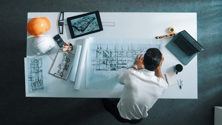 Top view of civil engineer drawing and measuring blueprint by using ruler. Aerial view of architect...