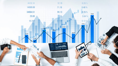 A business team engages in data analysis using laptops, reports, and charts, demonstrating effective...
