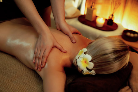 Closeup woman customer enjoying relaxing anti-stress spa massage and pampering with beauty skin recreation leisure in warm candle lighting ambient salon spa at luxury resort or hotel. Quiescentの写真素材