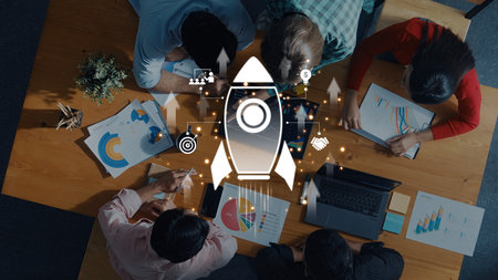 Dynamic teamwork environment capturing a brainstorming session, featuring data charts and a rocket graphic symbolizing growth and innovation in business.の写真素材