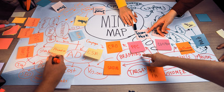 A dynamic group engages in brainstorming using colorful sticky notes to create an elaborate mind map, showcasing teamwork and innovative thought in a creative environment.の写真素材