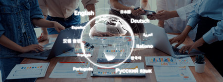 A dynamic business environment showcases teamwork and collaboration with laptops and charts, emphasizing a multilingual approach to global communication and problem-solving.の写真素材