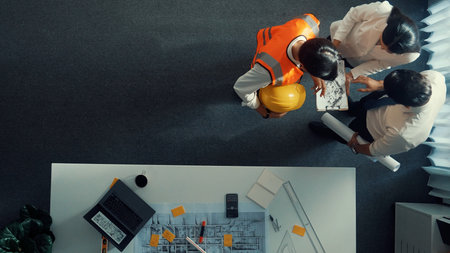 Top down view of caucasian project manager looking at house design while engineer joining meeting....