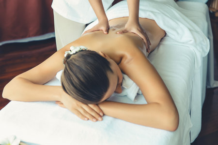 Caucasian woman customer enjoying relaxing anti-stress spa massage and pampering with beauty skin recreation leisure in day light ambient salon spa at luxury resort or hotel. Quiescentの写真素材