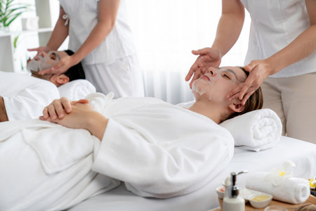 Serene modern daylight ambiance of spa salon, couple customer indulges in rejuvenating with facial skincare mask. Facial skin treatment and beauty cosmetology procedure for face. Quiescentの写真素材