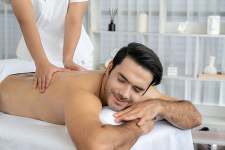 Caucasian man customer enjoying relaxing anti-stress spa massage and pampering with beauty skin recreation leisure in day light ambient salon spa at luxury resort or hotel. Quiescentの写真素材