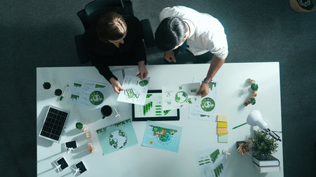 Top down view of business man presenting sustainable idea to manager by using tablet display. Manager working together planning to use clean energy.の写真素材