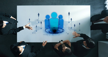 A group of business professionals engages in a collaborative meeting, showcasing teamwork and innovative ideas with digital elements in a modern workspace environment.の写真素材