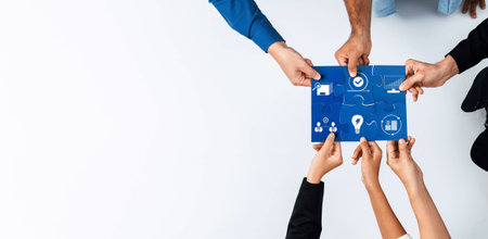 A diverse group of hands coming together to hold a blue puzzle piece displaying business strategy graphics, symbolizing teamwork, collaboration, and innovative solutions in the workplace.の写真素材