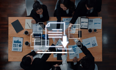 A top-down view of a professional business team analyzing data and collaborating on strategy, surrounded by documents, graphs, and modern technology.の写真素材