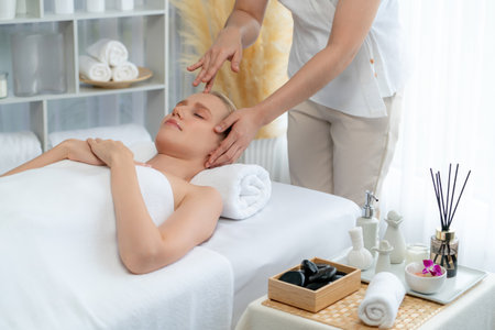 Caucasian woman enjoying relaxing anti-stress head massage and pampering facial beauty skin recreation leisure in dayspa modern light ambient at luxury resort or hotel spa salon. Quiescentの写真素材