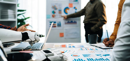A modern workspace featuring a robotic arm assisting in data analysis, illustrating teamwork and innovation in a business environment with charts and graphs.の写真素材