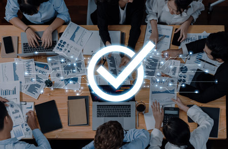 A diverse team collaborates at a modern office desk, reviewing graphs and reports, with a glowing checkmark symbolizing successful business strategies for optimal growth.の写真素材
