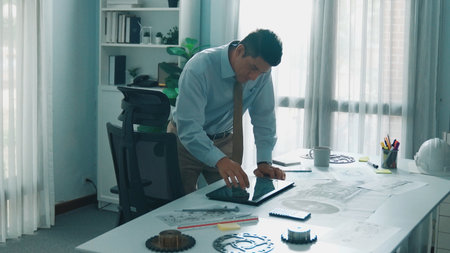 Top down aerial view of smart engineer calling manager about turbine engine structure while looking...
