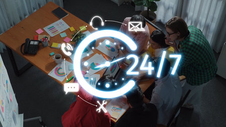 A group of professionals collaboratively working around a desk filled with charts and notes,...