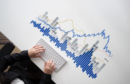 A business professional analyzes data trends using a keyboard in a modern office setting, showcasing...