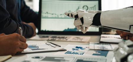 A robot collaborates with humans in a modern office, focusing on data analysis. Graphical representations and charts symbolize teamwork and innovation in business settings.の写真素材