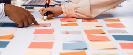 Two hands engage with colorful sticky notes on a table, showcasing a vibrant brainstorming session in a collaborative workspace to generate innovative ideas and strategies.の写真素材