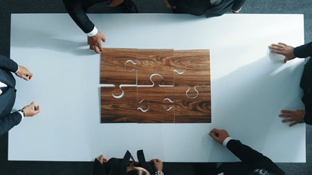 Top view of business people putting jigsaw together at meeting room. Professional marketing team standing at table while gathering puzzle piece. Show unity, cooperation and team working. Directorate.の写真素材