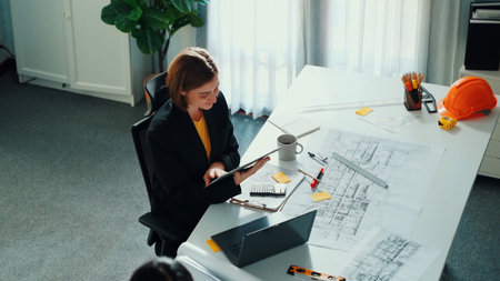 Top view of smart business woman walking and give house design. Aerial view of architect engineer looking at blueprint and building structure at table with safety helmet and house model.の写真素材