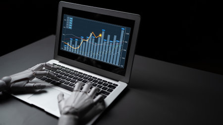 A robotic hand interacts with a laptop displaying dynamic graphs and charts, symbolizing advanced technology in data analysis and automation in a modern workspace.の写真素材