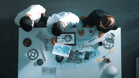 Top down view of skilled engineer working together while looking at jet engine. Aerial view of smart designer or diverse technicians brainstorming.の写真素材