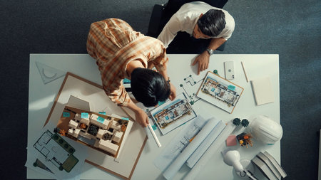 Top down view of skilled businessman and colleague designing house together. Aerial view of architect engineer working and measuring building structure by using architectural equipment.の写真素材