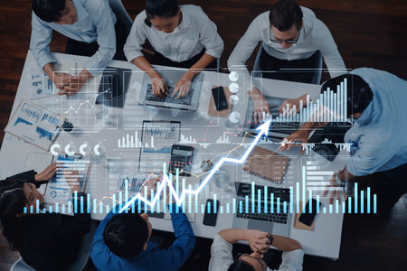 A top-down view of a business team engaged in collaborative work, analyzing financial trends and...