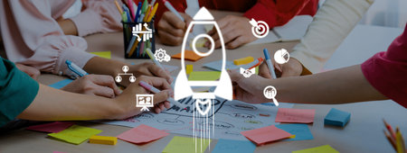 A diverse group engaged in a creative brainstorming session using colorful notes and markers. The rocket illustration represents innovative thinking and the drive for success.の写真素材
