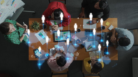 Overhead view of a collaborative team working in a modern office space, integrating digital elements to enhance communication and innovation during meetings. Rasterの写真素材