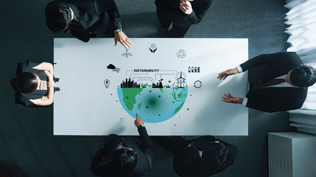 A diverse business team collaborates in a modern office setting to discuss sustainability strategies, illustrated with a green globe and eco-friendly icons.の写真素材