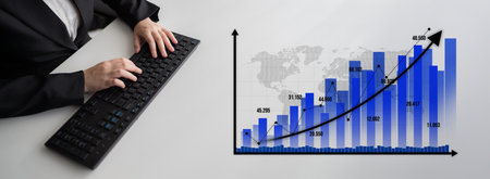 A business professional types on a laptop while analyzing a vibrant financial growth chart. The...