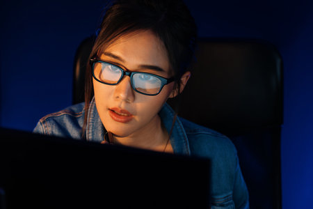 Portrait young beautiful Asian creative with glasses of serious face looking on pc to search project...
