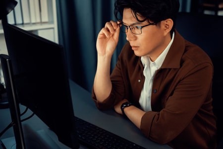Smart businessman in casual day focusing on computer to create a business plan report over late night time at office, working on searching tools market planning with new startup company project.の写真素材