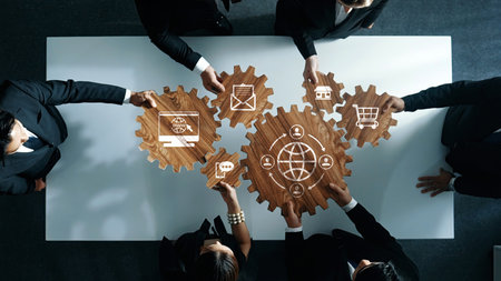 A top-down view of a diverse team engaging in strategic collaboration using wooden gears and digital...