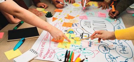 A dynamic scene showcasing a diverse group engaged in a brainstorming session, surrounded by colorful sticky notes and a detailed mind map on a wooden desk.の写真素材