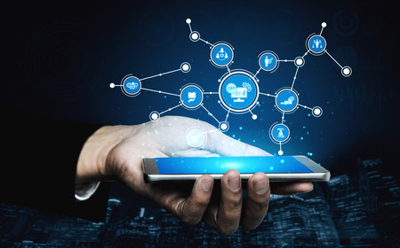 A hand holds a smartphone displaying digital connection icons, symbolizing technology integration,...